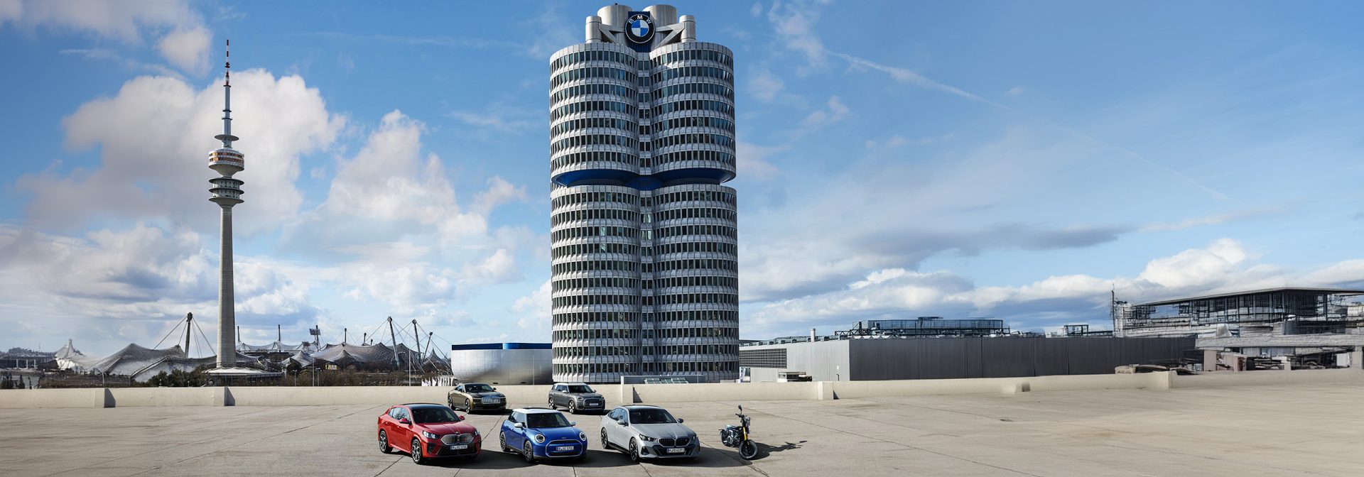 View of the BMW four-cylinder building with parked vehicles in front.