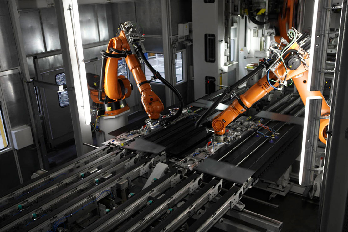 Robotic arms are working on metall parts.