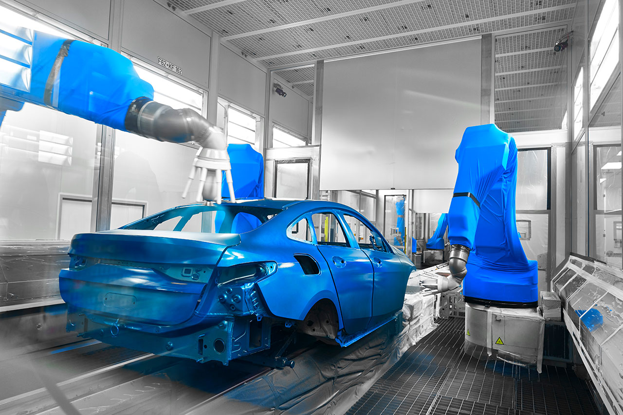 Robotic arms are painting a car body in blue.