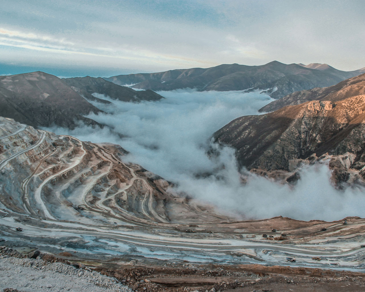 White snow covers the mountains, while clouds gently drift overhead, shrouding the landscape.