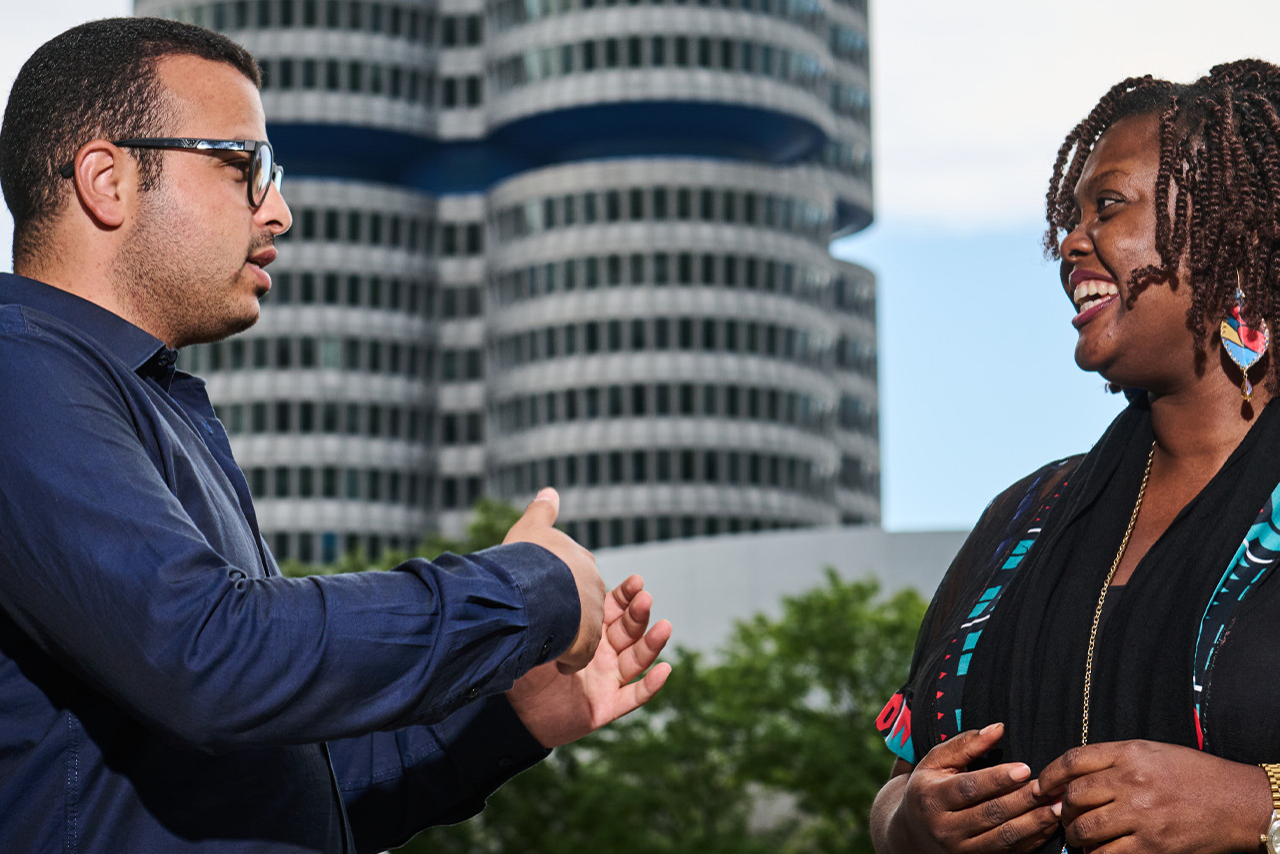 A man and a woman are talking in front of the BMW building.