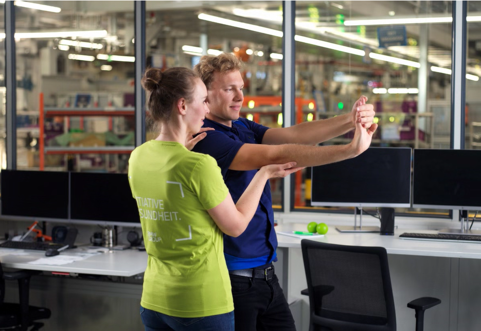 A trainer helps an employee perform exercises.