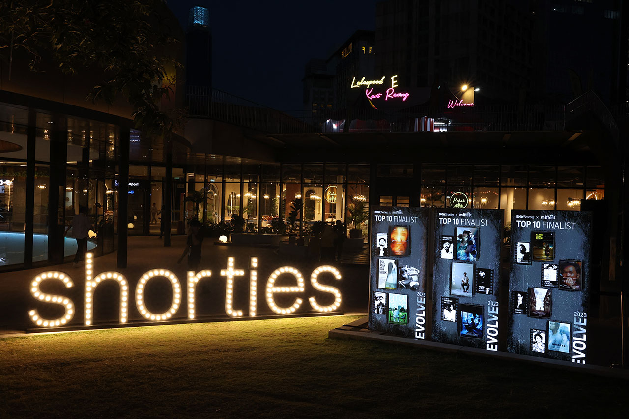 illuminated letters ‘shorties’ in front of a modern building and information boards next to it