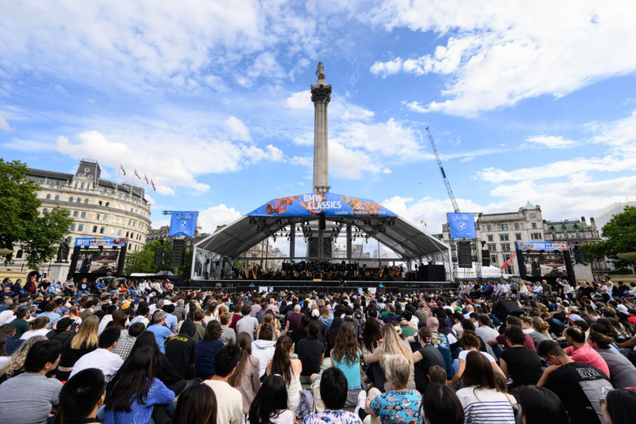A huge crowd listening to a concert outdoors.