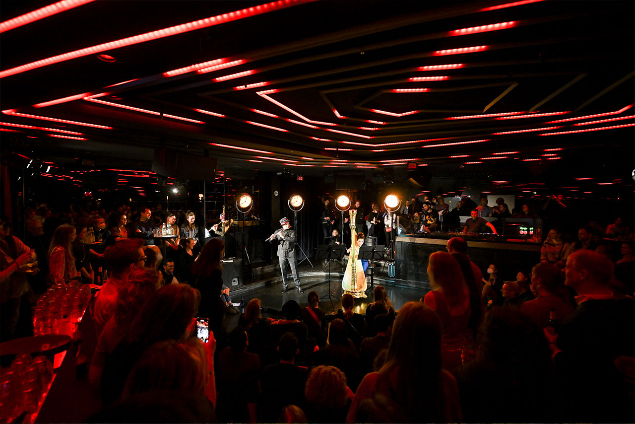 A concert for a smaller group of people. A modern BMW X3 and a historic Isetta are parked next to the stage