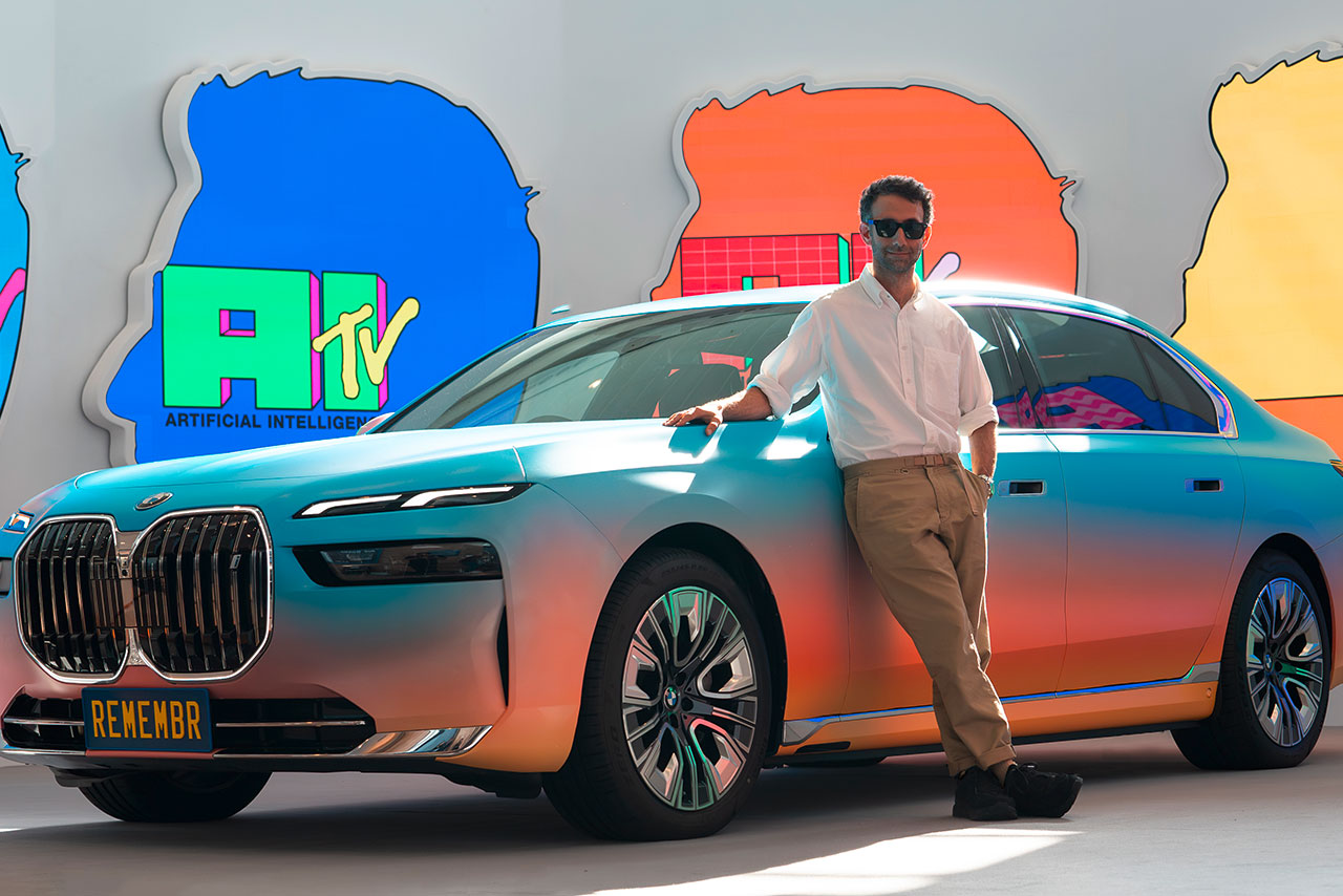 Modern BMW 7 Series with colour gradient from blue to coral, on which a man is leaning.