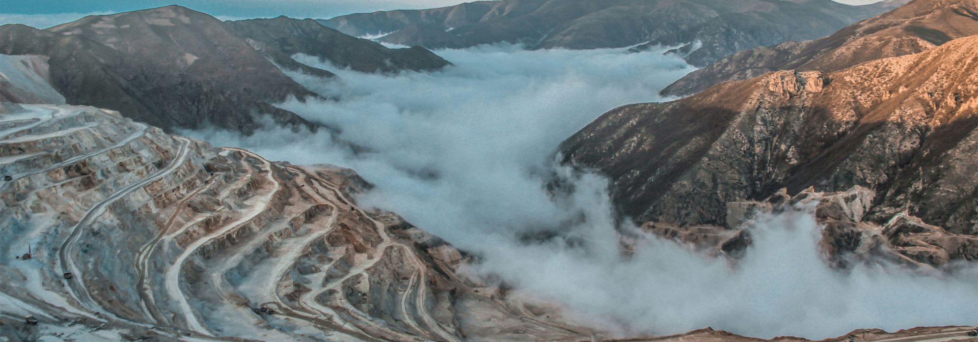 A snow-covered mountain range surrounded by dense clouds, forming a majestic landscape.