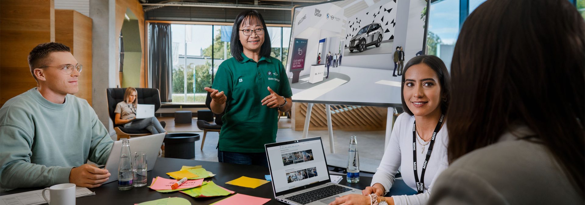 Several people gather around a table with a laptop on it.