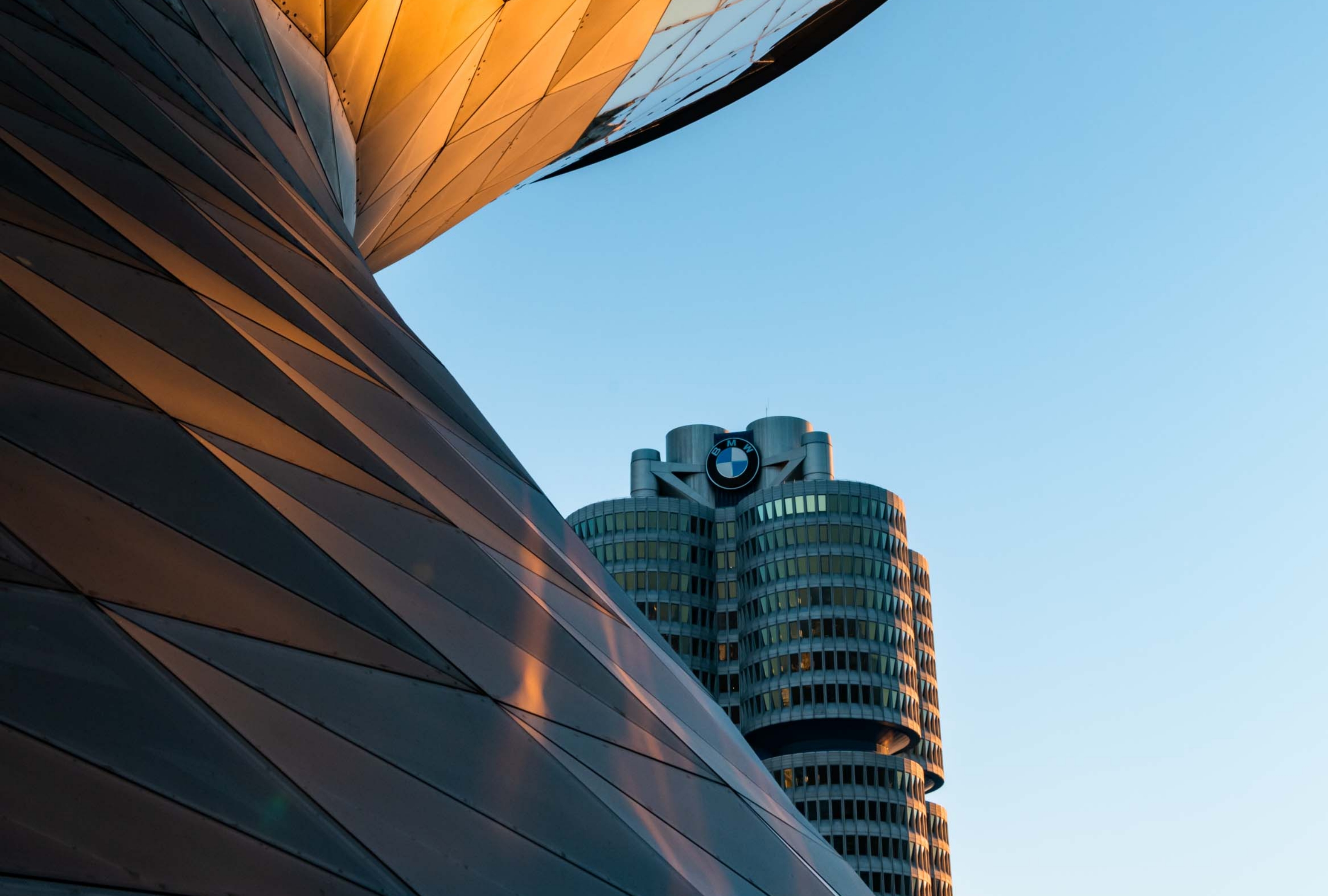 Im Vordergrund ist die Doppelkegel-Eventlocation der BMW Welt angeschnitten, im Hintergrund die BMW Zentrale München.