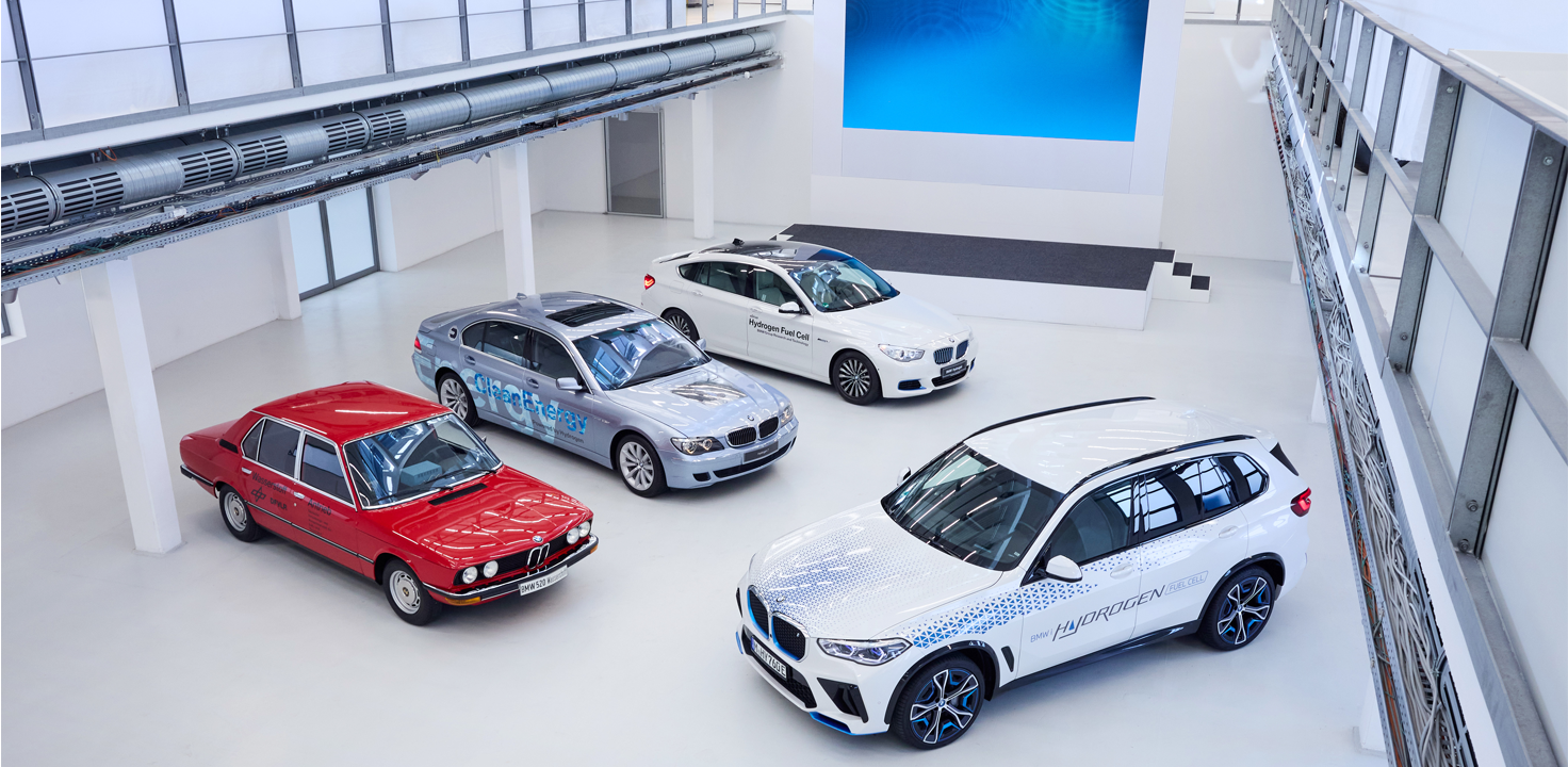 Verschiedene Wasserstoff Fahrzeuge – von historisch bis modern stehen zusammen in einer Halle