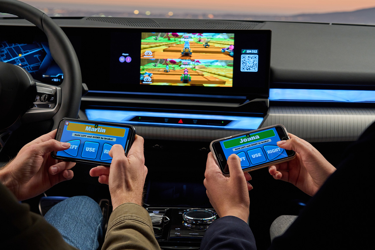 Zwei Personen spielen ein Spiel mit ihren Smartphones auf dem BMW In-Car Display