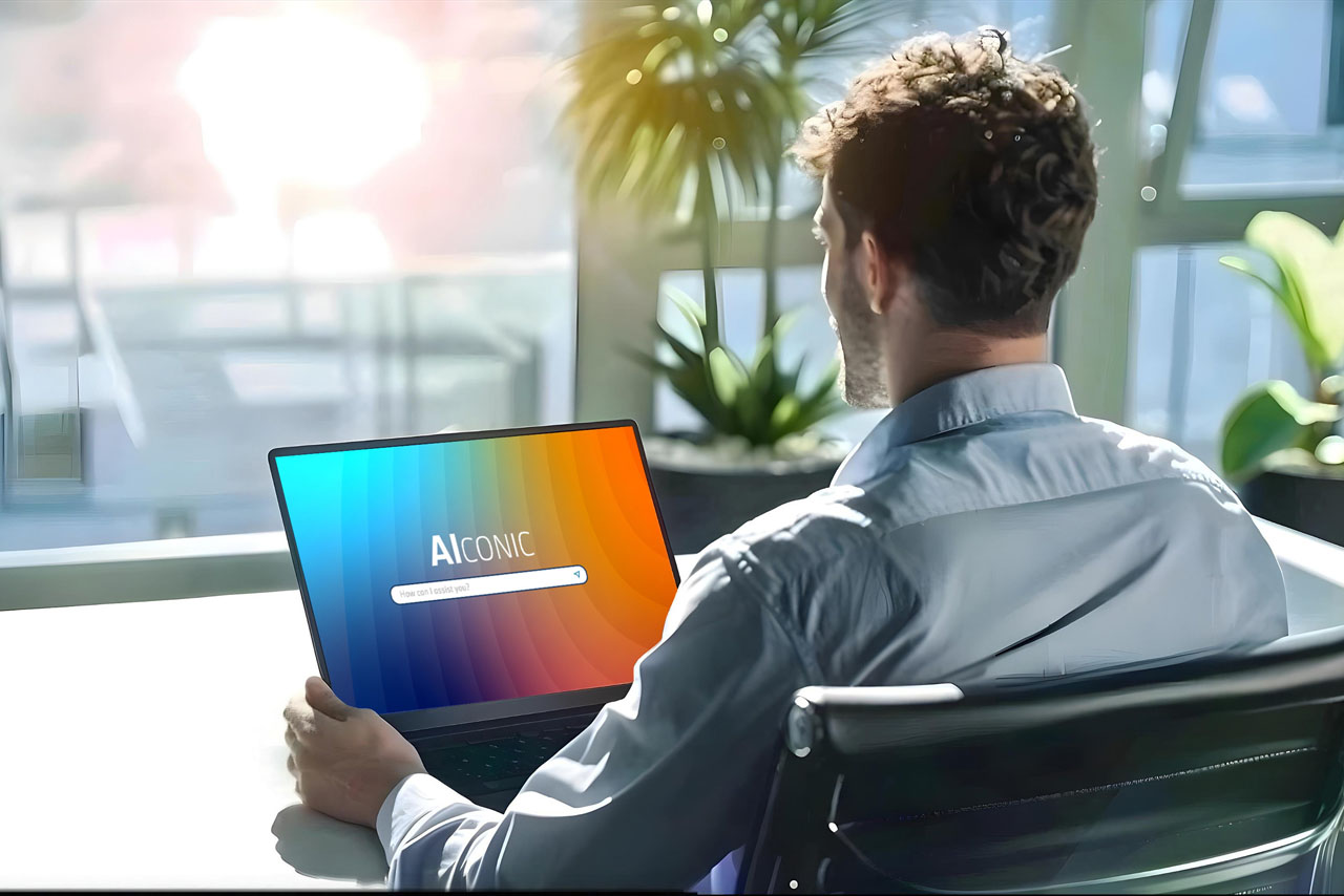 Ein Mann arbeitet an einem Laptop, während er an einem Schreibtisch sitzt.
