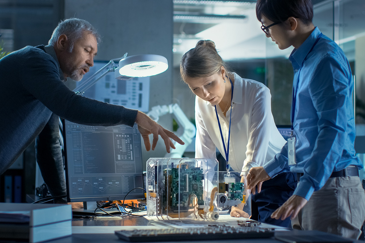 Ein Team von Computeringenieuren lehnt sich an den Schreibtisch und wählt Leiterplatten für die Arbeit aus.