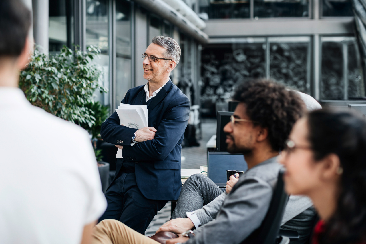 Ein Mann im Anzug spricht mit einer Gruppe von Menschen.