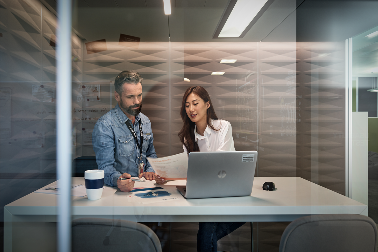 Ein Mann und eine Frau sitzen an einem Tisch mit einem Laptop und diskutieren.