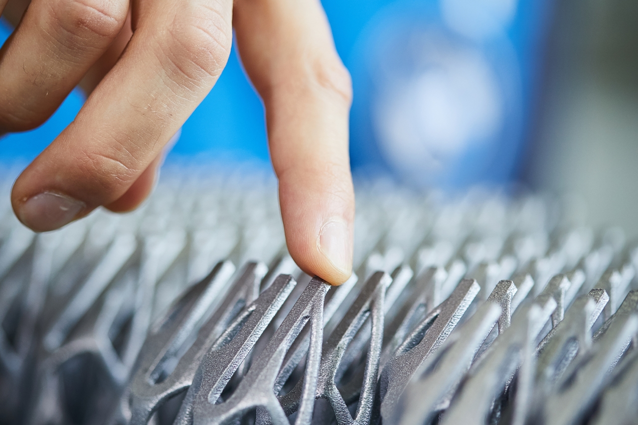 Eine Hand berührt per 3D-Druck hergestellte Bauteile.
