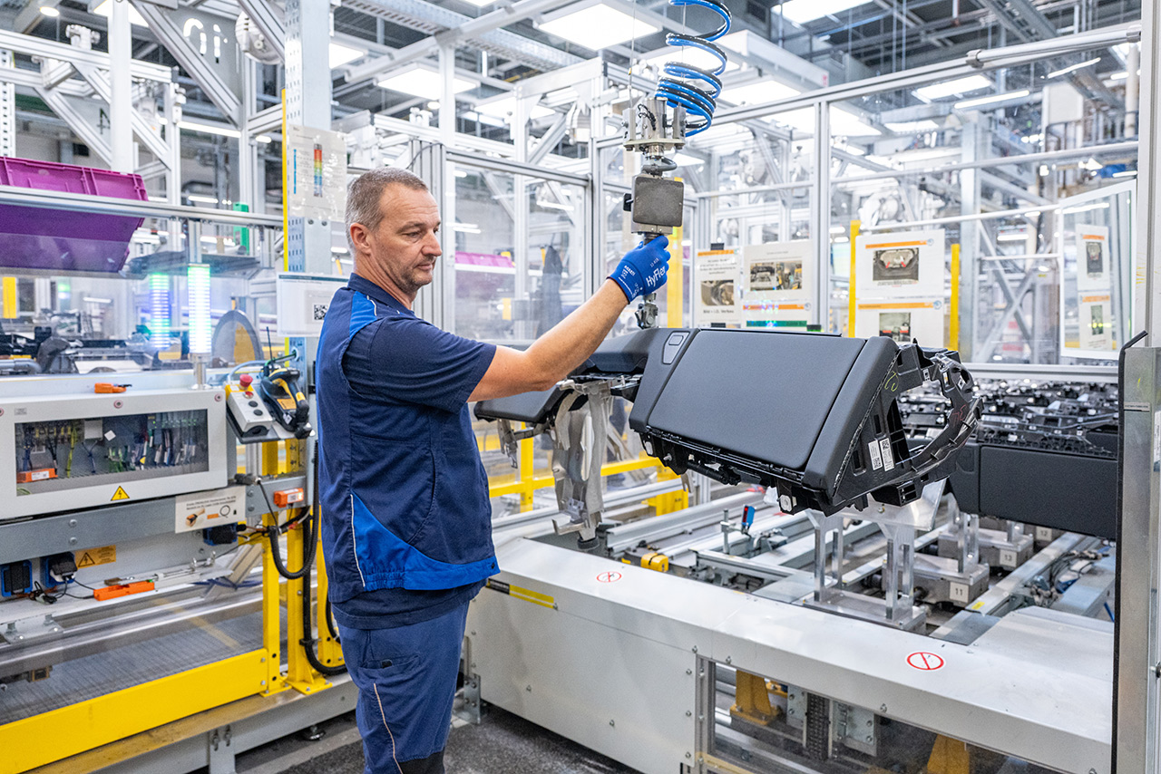 BMW Group Werk Landshut Mitarbeiter bedient die Maschine zur smarten Cockpit Produktion.