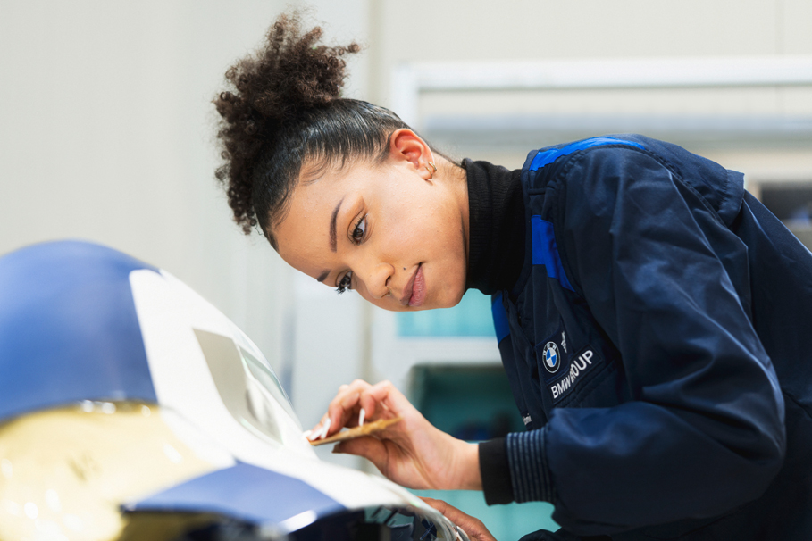 BMW Group employee is concentrated working on a car part.