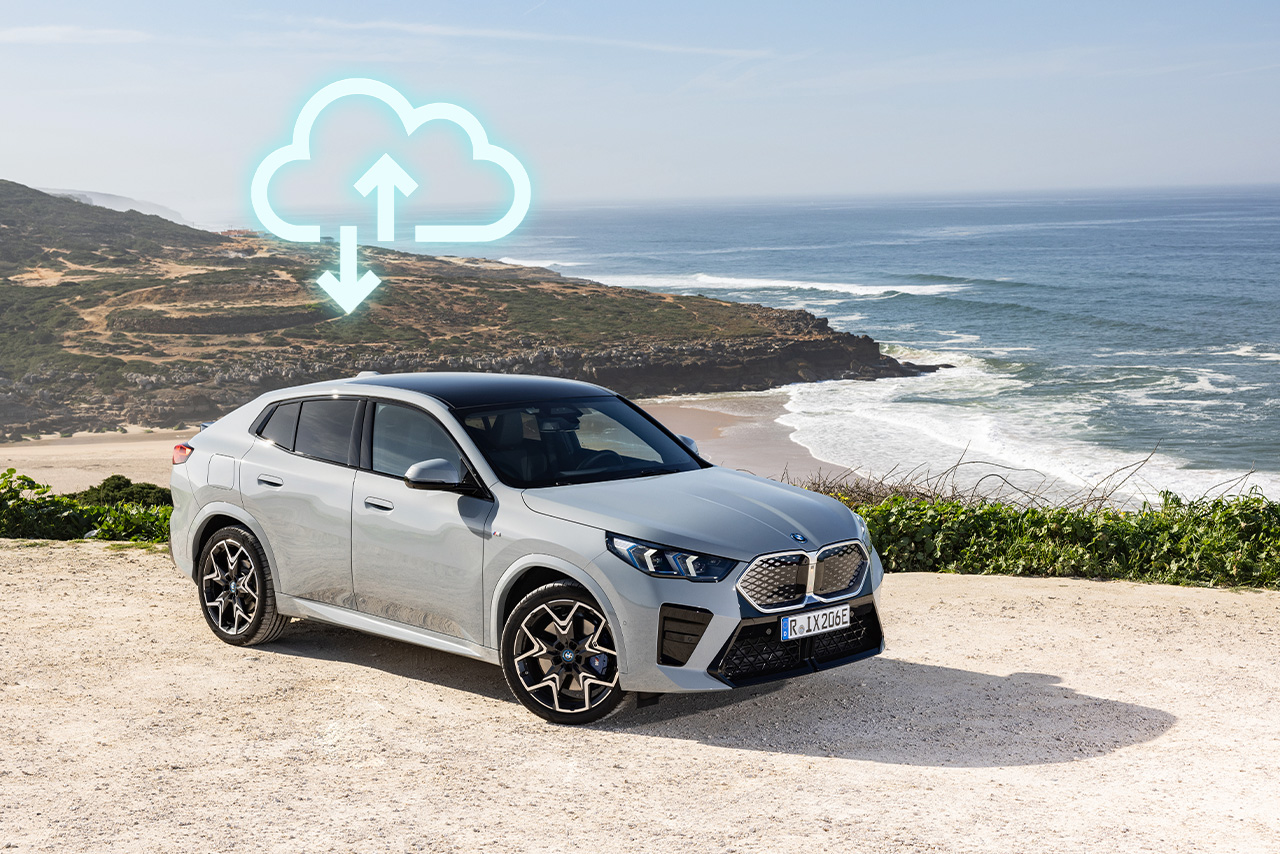 A modern BMW vehicle standing next to the sea with an upload icon on top.