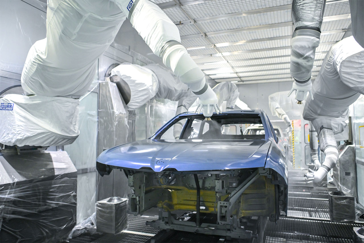 Robots in the paint shop at BMW Group Plant Debrecen spray the bonnet of a BMW iX3 in blue.